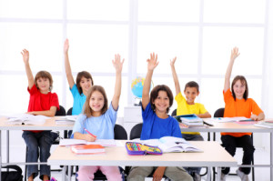 School children raising hands in a modern classroom.